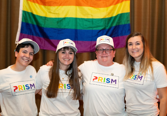 PRISM members gathered in front of a flag